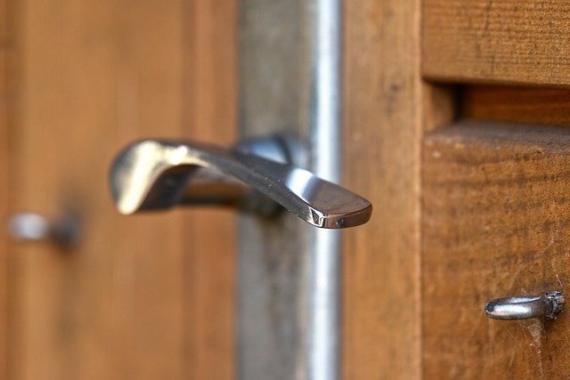 Detail na striebornú kľučku a zámok na hnedých dverách.jpg