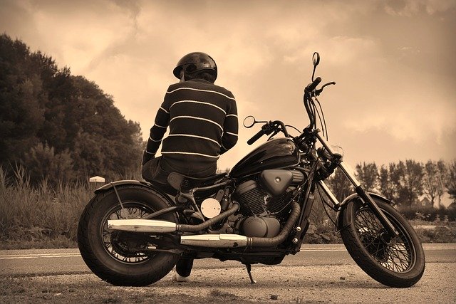 Chlap v prilbe sedí na odparkovanej motorke