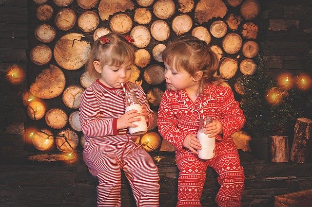 Dve dievčatá v červených pyžamách pijú mlieko