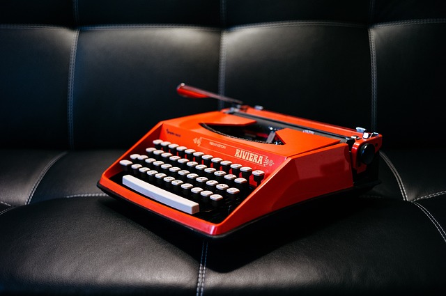 Červený písací stroj na čiernej koženej pohovke