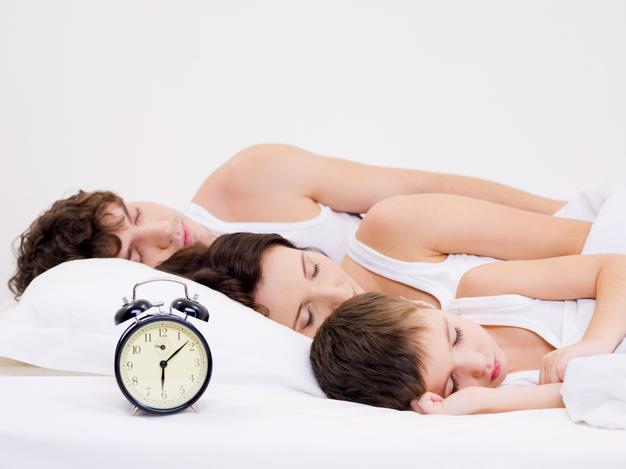 three-person-young-family-sleeping-with-alarm-clock-near-their-heads_186202-8720